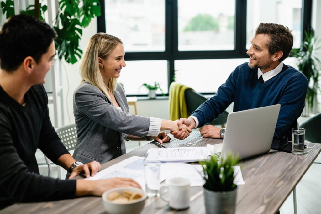 Young Happy Couple Meeting With Financial Advisor Office Woman Is Handshaking With Agent.jpg